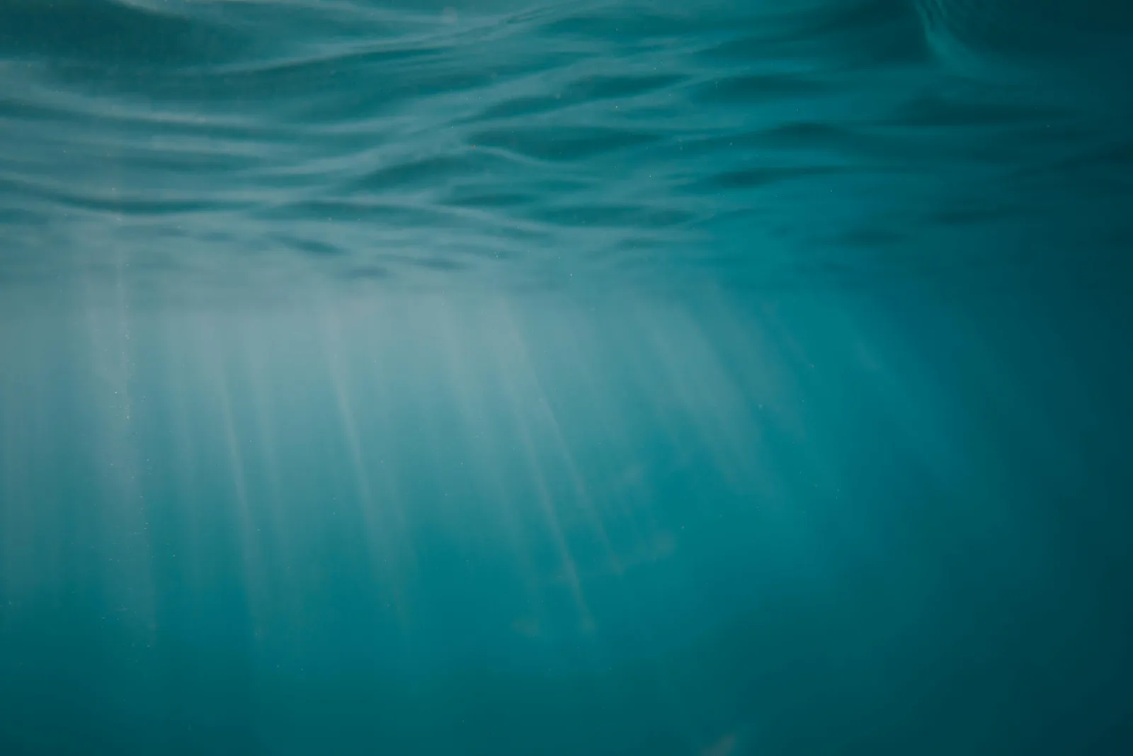 Rays of light falling through blue water, accompanying an article on the inner experience of a hypnosis session