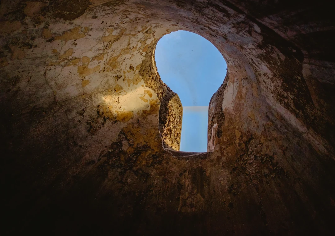 Daylight falling through a keyhole-shaped opening in a stone wall
